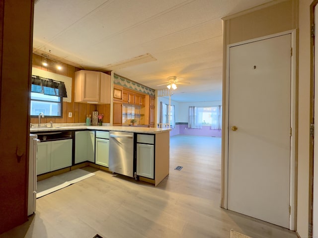 kitchen with ceiling fan, light wood-style flooring, a peninsula, light countertops, and a sink