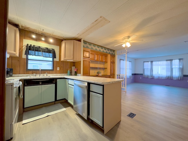 kitchen with stove, a peninsula, light wood-type flooring, light countertops, and a sink