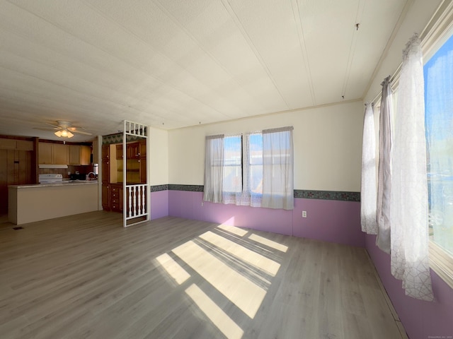 empty room with wood finished floors, ceiling fan, and a wainscoted wall