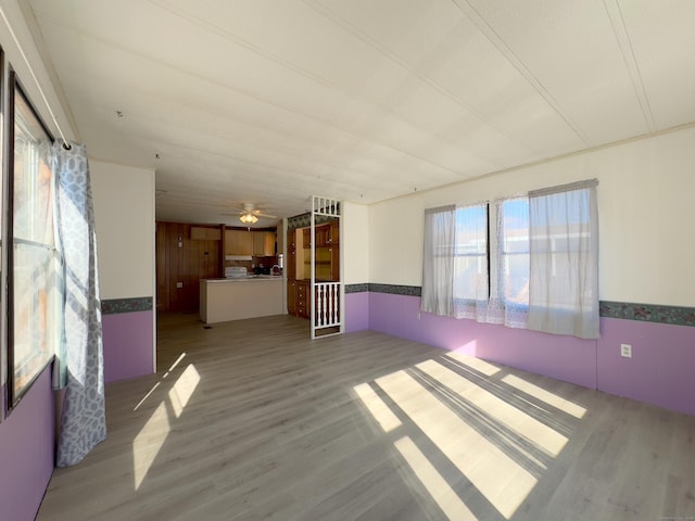 unfurnished living room featuring a wainscoted wall and light wood-style flooring