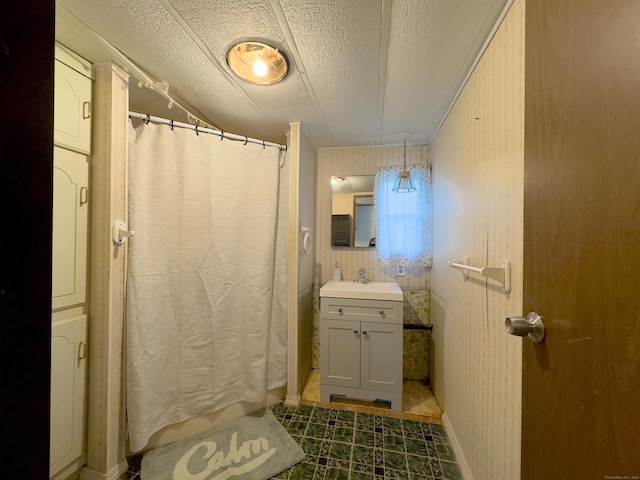 full bathroom featuring a shower with shower curtain, wallpapered walls, a textured ceiling, and vanity