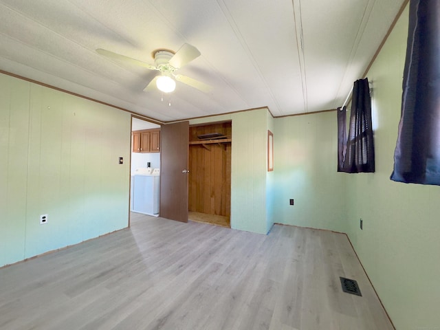 unfurnished bedroom featuring crown molding, visible vents, light wood-style flooring, a ceiling fan, and washer / dryer