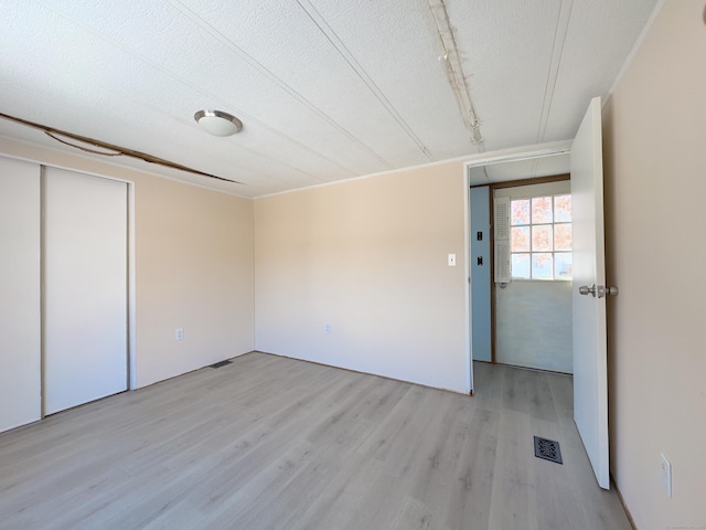 spare room featuring visible vents, light wood finished floors, rail lighting, and a textured ceiling
