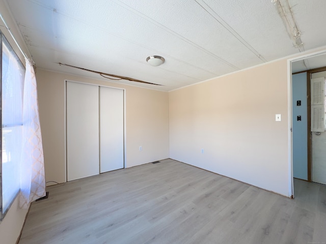unfurnished bedroom featuring light wood-style floors, a closet, and a textured ceiling