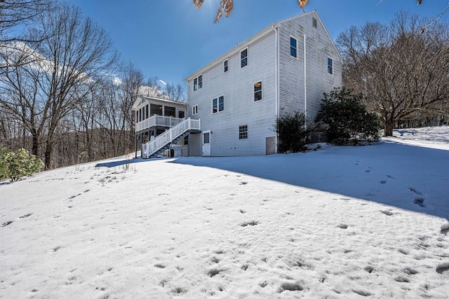 snow covered house featuring stairway