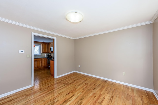 unfurnished room with baseboards, crown molding, and light wood-style floors