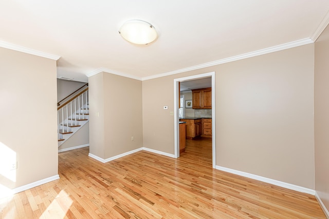 unfurnished room featuring stairs, crown molding, light wood-style flooring, and baseboards