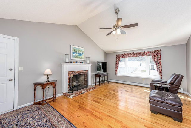 living area with lofted ceiling, ceiling fan, a baseboard radiator, a fireplace, and wood finished floors