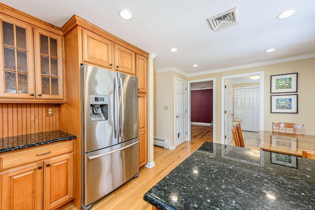 kitchen featuring visible vents, baseboard heating, dark stone countertops, stainless steel fridge, and glass insert cabinets