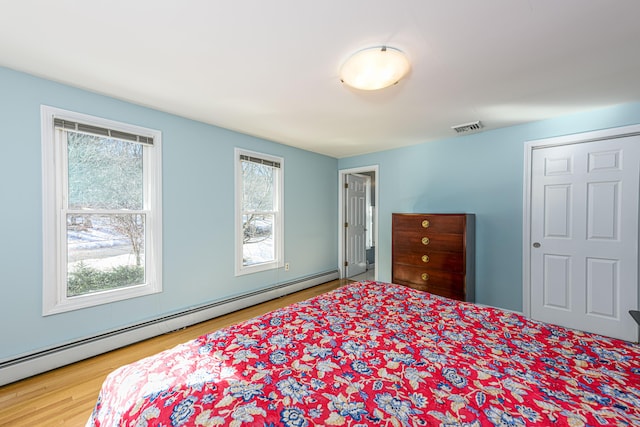 bedroom featuring a baseboard radiator, visible vents, and wood finished floors