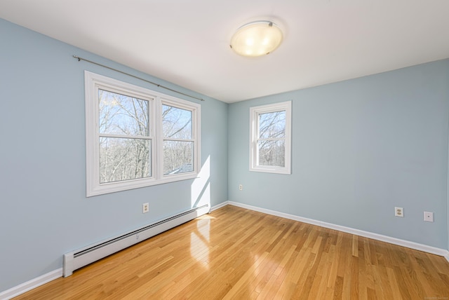 unfurnished room featuring a baseboard radiator, baseboards, and light wood finished floors