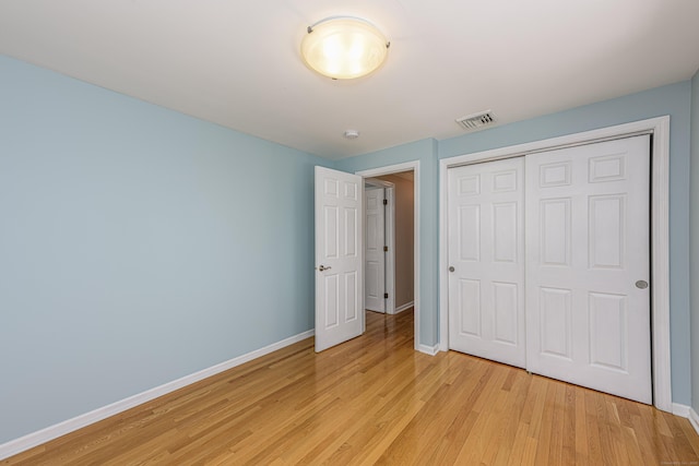 unfurnished bedroom featuring a closet, visible vents, light wood-style flooring, and baseboards