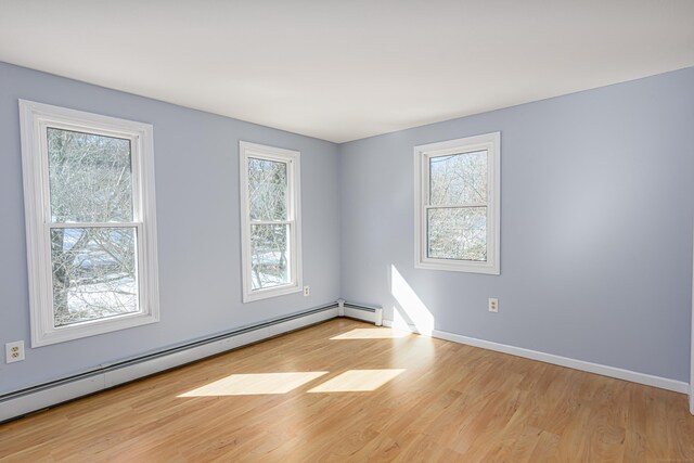 empty room featuring a baseboard radiator, wood finished floors, and baseboards