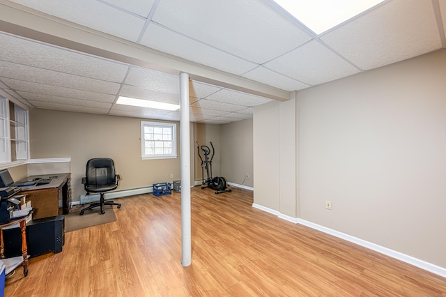 office area featuring light wood-style floors, a paneled ceiling, a baseboard heating unit, and baseboards