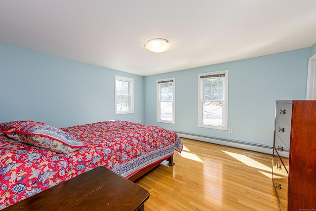 bedroom with a baseboard heating unit and wood finished floors