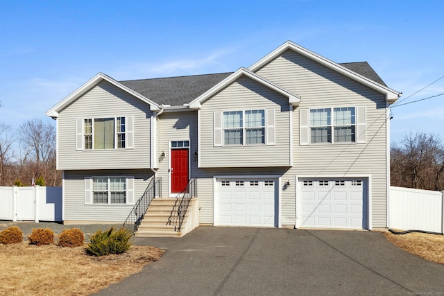 bi-level home with driveway, a garage, and fence