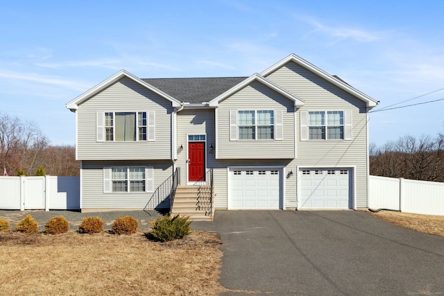 bi-level home with a gate, driveway, a garage, and fence