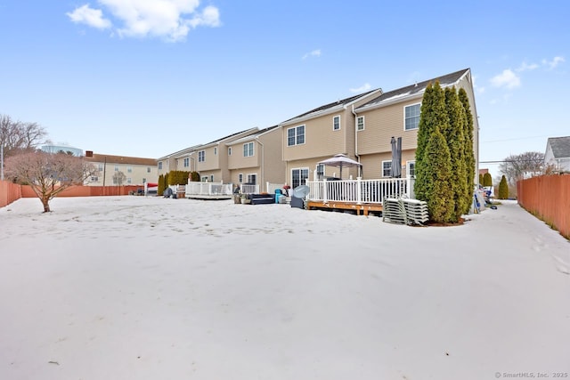 snow covered house featuring a residential view, fence, and a wooden deck