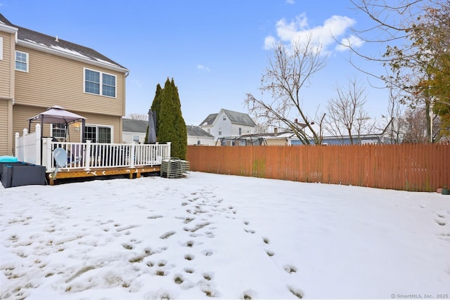 yard covered in snow featuring fence and a wooden deck