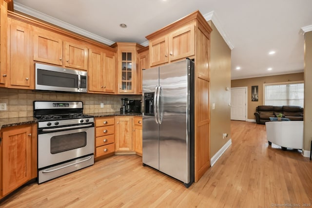 kitchen featuring light wood finished floors, decorative backsplash, dark stone counters, glass insert cabinets, and stainless steel appliances