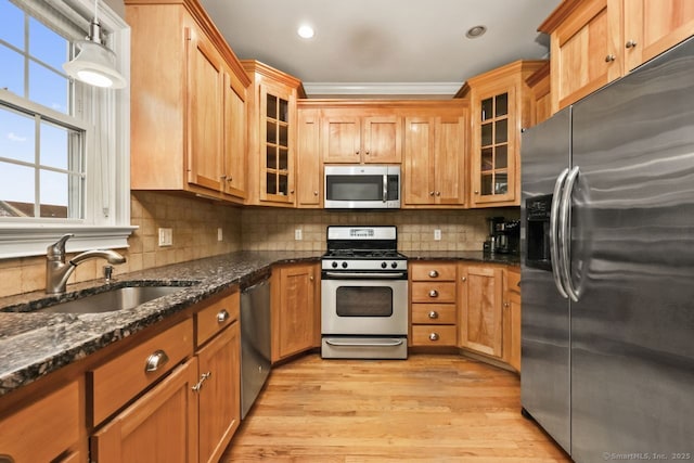 kitchen featuring stainless steel appliances, a wealth of natural light, light wood-type flooring, and a sink