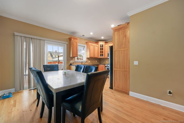 dining space featuring light wood finished floors, baseboards, crown molding, and recessed lighting