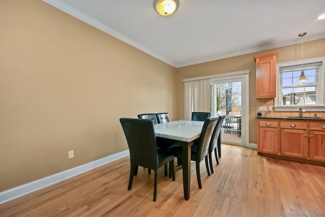 dining room with baseboards, light wood-style flooring, and crown molding