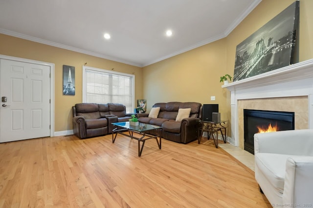 living room featuring light wood-style floors, baseboards, crown molding, and a tile fireplace