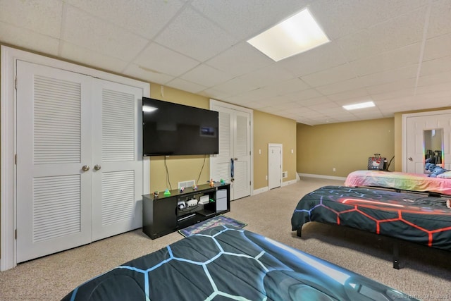 bedroom featuring carpet, a drop ceiling, and baseboards