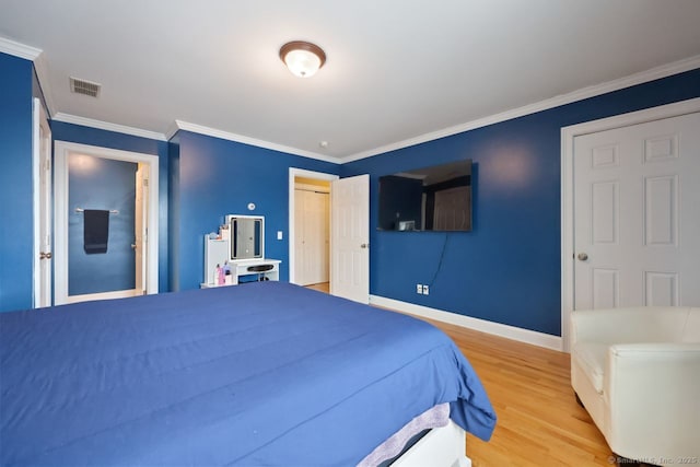 bedroom with baseboards, visible vents, ornamental molding, wood finished floors, and a closet