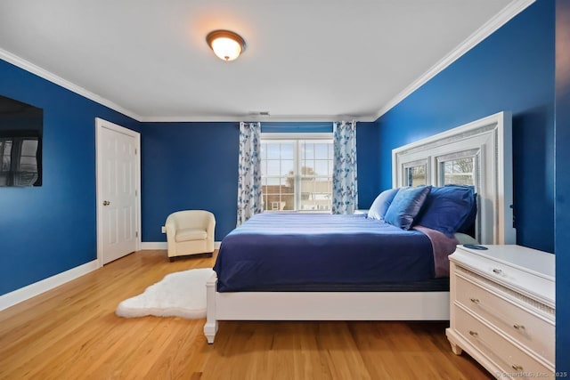 bedroom with visible vents, crown molding, baseboards, and wood finished floors