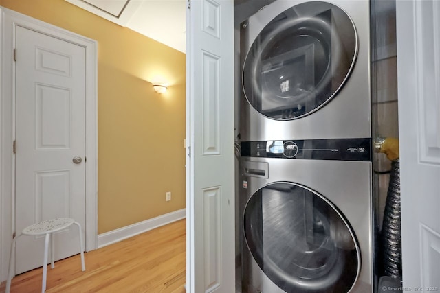 laundry room with stacked washer / dryer, laundry area, baseboards, and wood finished floors