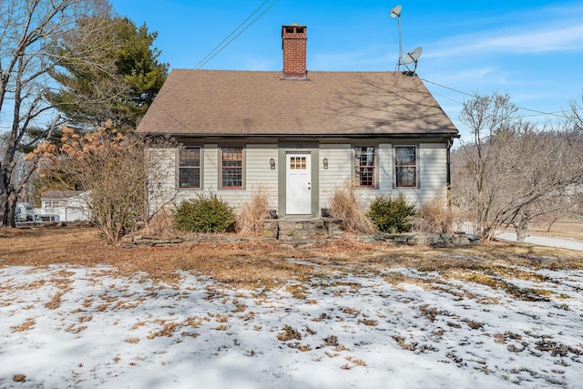 view of front facade featuring a shingled roof and a chimney