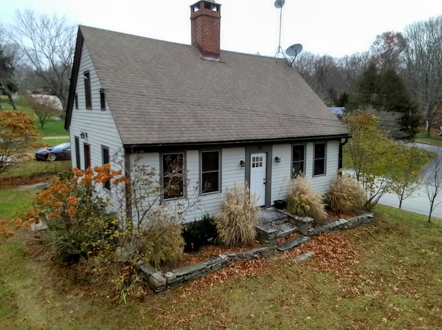 cape cod home with a shingled roof and a chimney