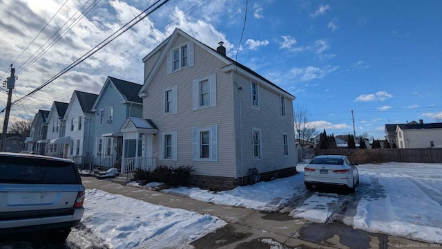 snow covered property featuring a residential view and a chimney