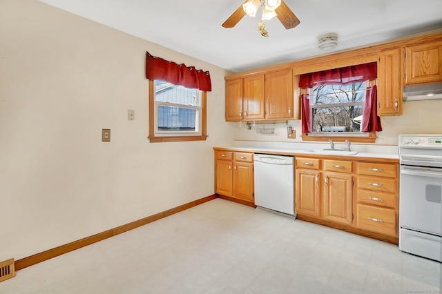 kitchen with under cabinet range hood, white appliances, a sink, light countertops, and light floors