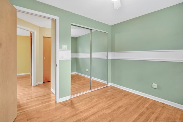 unfurnished bedroom with a closet, ceiling fan, baseboards, and wood finished floors