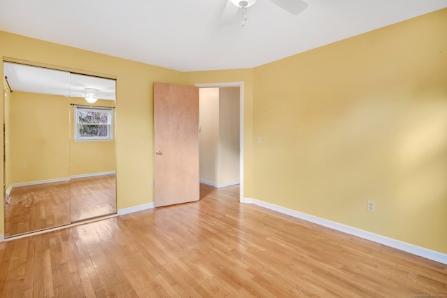 unfurnished bedroom featuring light wood finished floors, a ceiling fan, baseboards, and a closet