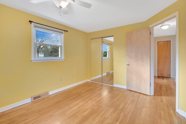 unfurnished bedroom with light wood-style flooring, multiple windows, visible vents, and baseboards