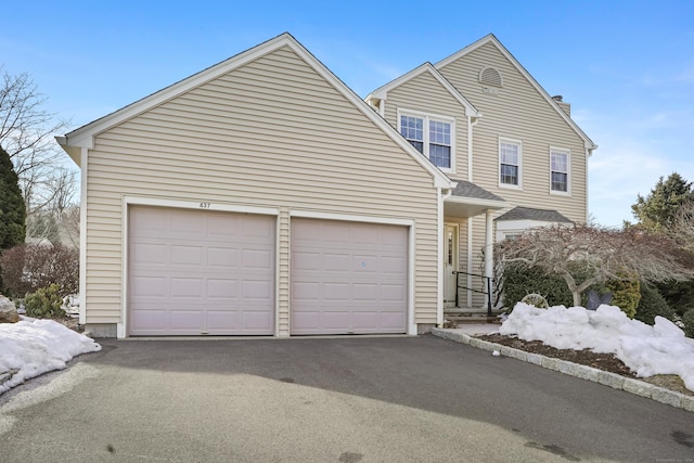 traditional-style home featuring driveway, a chimney, and an attached garage