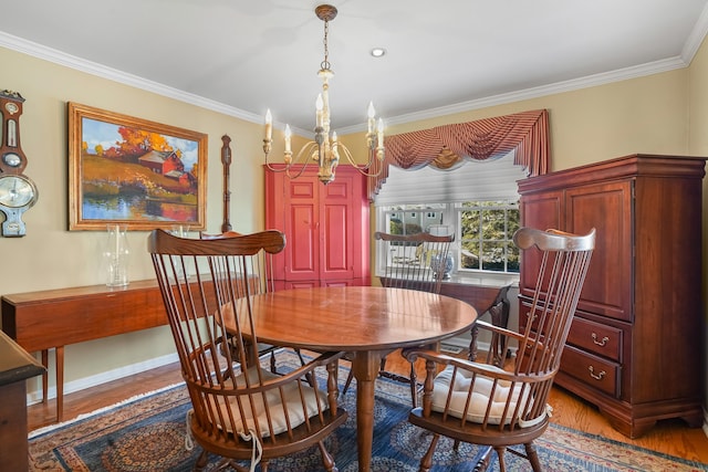 dining room with an inviting chandelier, baseboards, ornamental molding, and wood finished floors