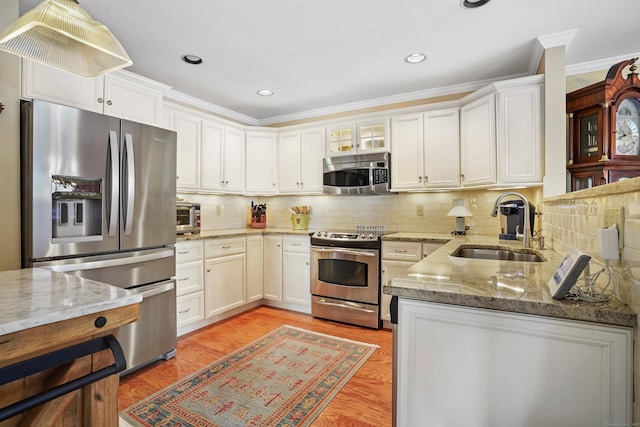 kitchen featuring light stone countertops, white cabinetry, appliances with stainless steel finishes, and a sink