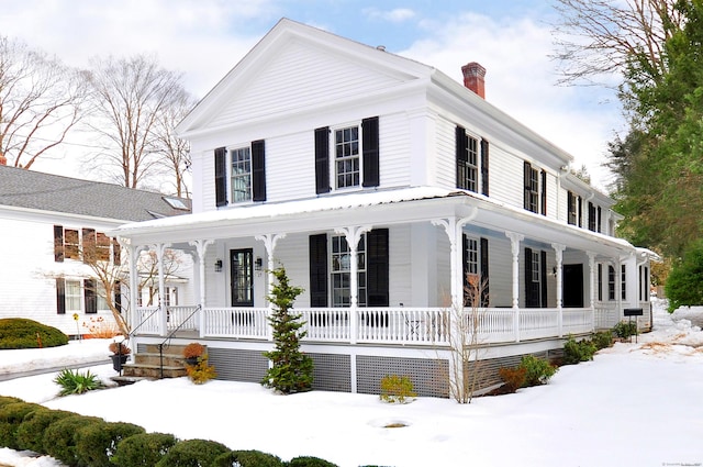 neoclassical home featuring a porch and a chimney