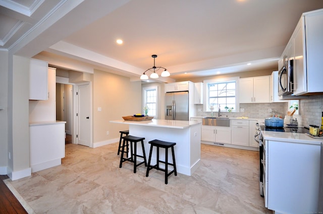 kitchen with appliances with stainless steel finishes, decorative backsplash, a sink, and a center island