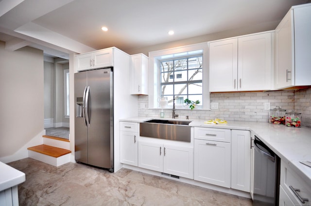 kitchen with visible vents, backsplash, appliances with stainless steel finishes, white cabinets, and a sink