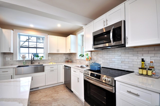 kitchen featuring light stone counters, a sink, visible vents, white cabinets, and appliances with stainless steel finishes