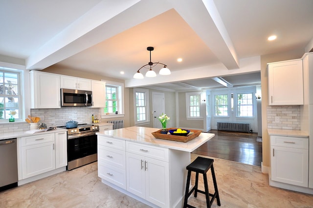 kitchen with radiator, white cabinetry, appliances with stainless steel finishes, and beamed ceiling