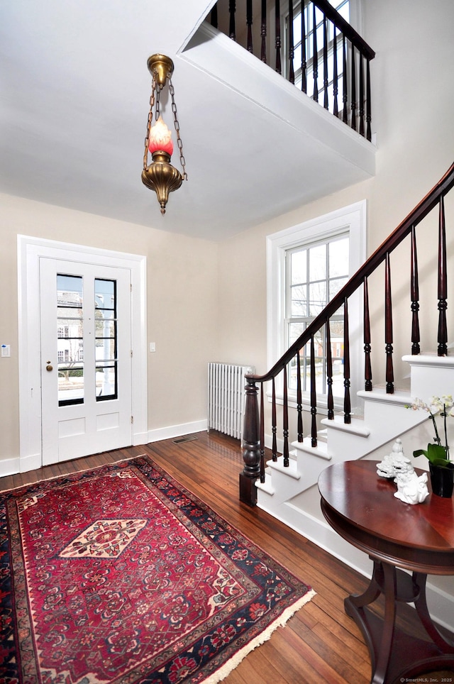 foyer entrance with radiator, a healthy amount of sunlight, and stairway