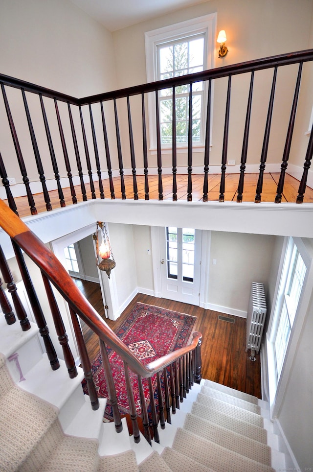 staircase featuring a healthy amount of sunlight, baseboards, visible vents, and wood finished floors