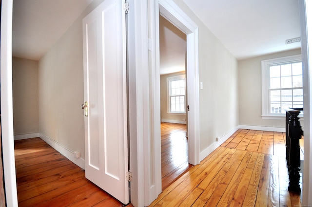 corridor featuring light wood-type flooring, visible vents, and baseboards